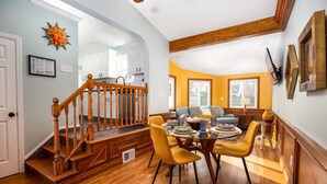 A dining area with a wooden staircase, yellow chairs, and a table set with dishes.