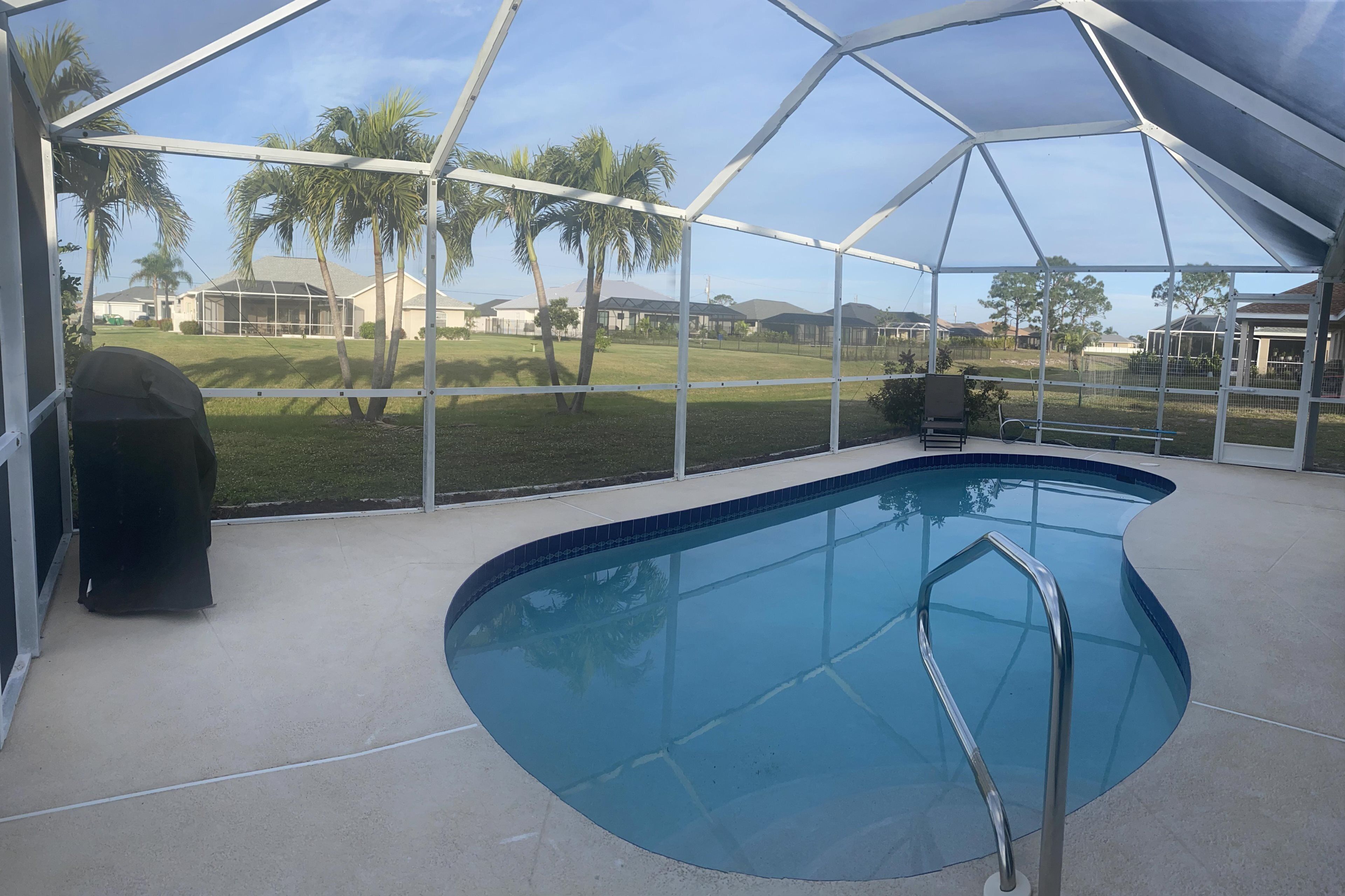 Una piscina interior con vista despejada del barrio circundante, incluyendo casas y palmeras.