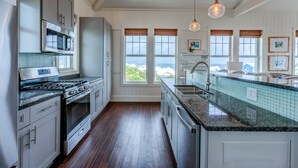 A modern kitchen with stainless steel appliances, a granite countertop, and large windows offering a view. - Sky High • Panoramic Views, Dock Slip, Steps to Tahiti Beach - Hope Town (Hope Town)
