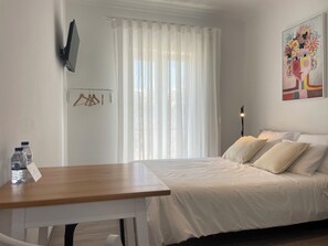 Une chambre à coucher avec un lit, une table sur laquelle se trouvent des bouteilles d’eau, une lampe et un tableau accroché au mur.