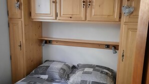 A bedroom with a bed, wooden cabinets, and a hanging light fixture. - Appartement Pied des Pistes (Châtel)