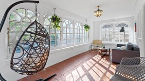 A sunlit room with a hanging chair, a sofa, and a table. - 1 Block to AC Beach - 8br/5ba Historic & Modern (Atlantic City)