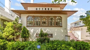 A two-story house with a wooden roof, large arched windows, and a stone wall in front. - 1 Block to AC Beach - 8br/5ba Historic & Modern (Atlantic City)