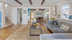 A spacious living room with hardwood floors, a sofa, a coffee table, and a staircase. - 1 Block to AC Beach - 8br/5ba Historic & Modern (Atlantic City)