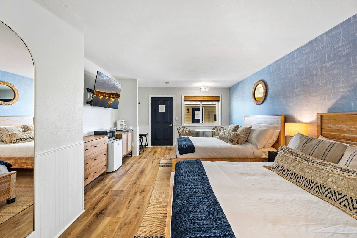 A bedroom with a large bed, a desk, a chair, and a television.