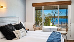 Un dormitorio con una cama grande, dos sillas, una mesita y vistas a un lago.