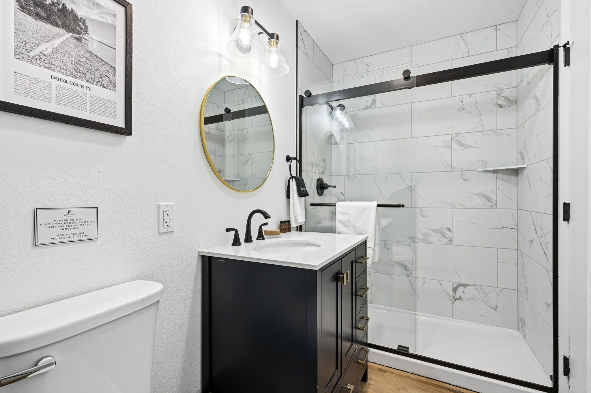 A modern bathroom with a toilet, sink, mirror, and shower.