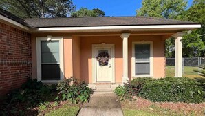 A single-story house with a front porch, a brick exterior, and a small front yard with shrubs. - BestStays@Bayou-Chic -work crews love us. Fenced with WIFI (Baton Rouge)