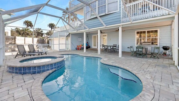 Una piscina con hidromasaje, rodeada por un patio con mobiliario exterior y una terraza cubierta.