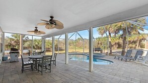 Un patio cubierto con piscina, mobiliario exterior y ventiladores de techo.