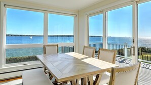 Un espace repas offrant une vue sur la mer grâce à de grandes fenêtres.