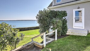 Une maison avec vue sur un lac, un petit escalier menant à l’entrée et une pelouse bien entretenue.