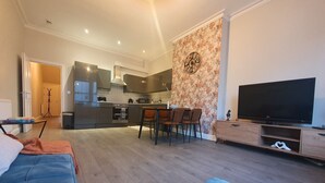 Un salon moderne avec un canapé, un téléviseur et un coin repas comprenant des chaises et une table.