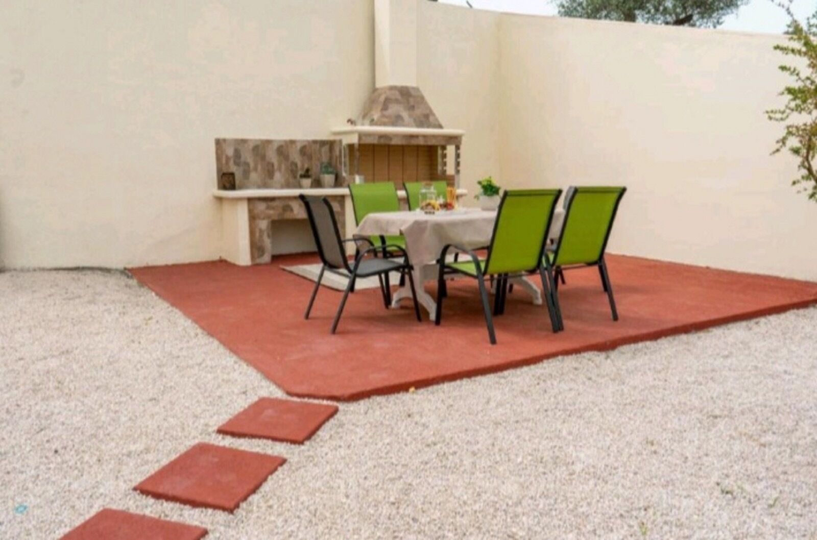 Een terras buiten met een tafel en stoelen, een barbecue en een stenen open haard.