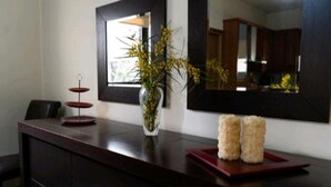 A reception desk with a vase of yellow flowers, a mirror, and two decorative items on a red tray.
