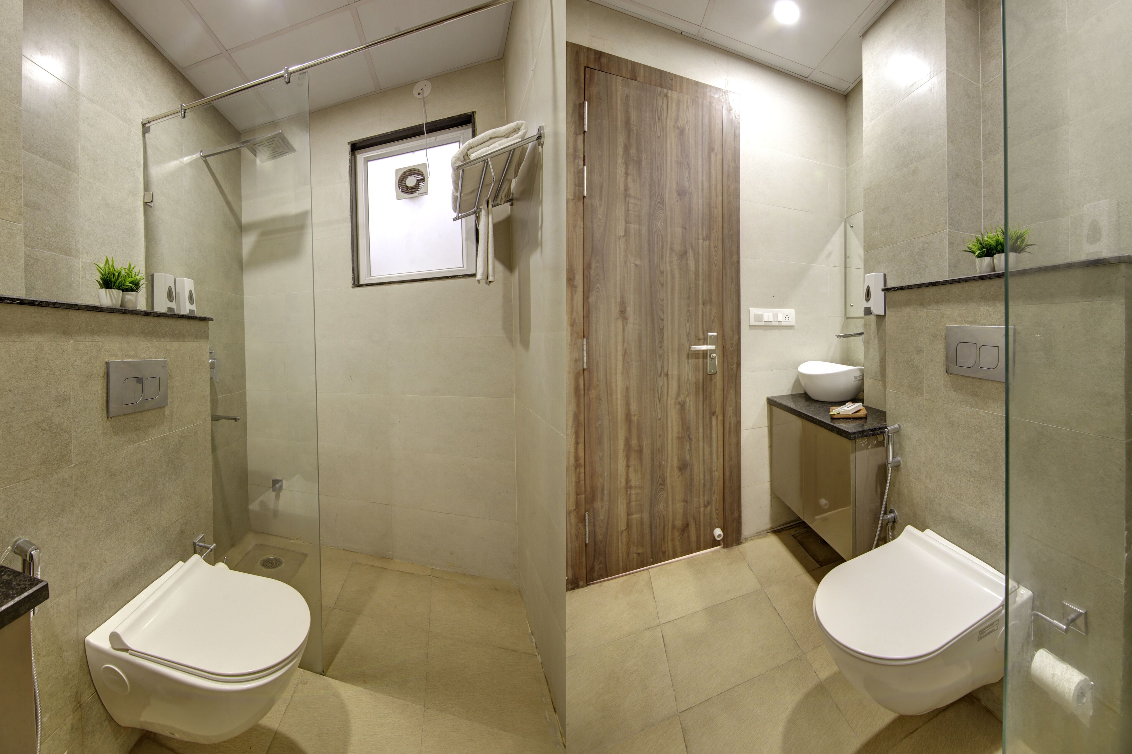 A modern bathroom with two toilets, a shower, a wooden door, and a small sink area.