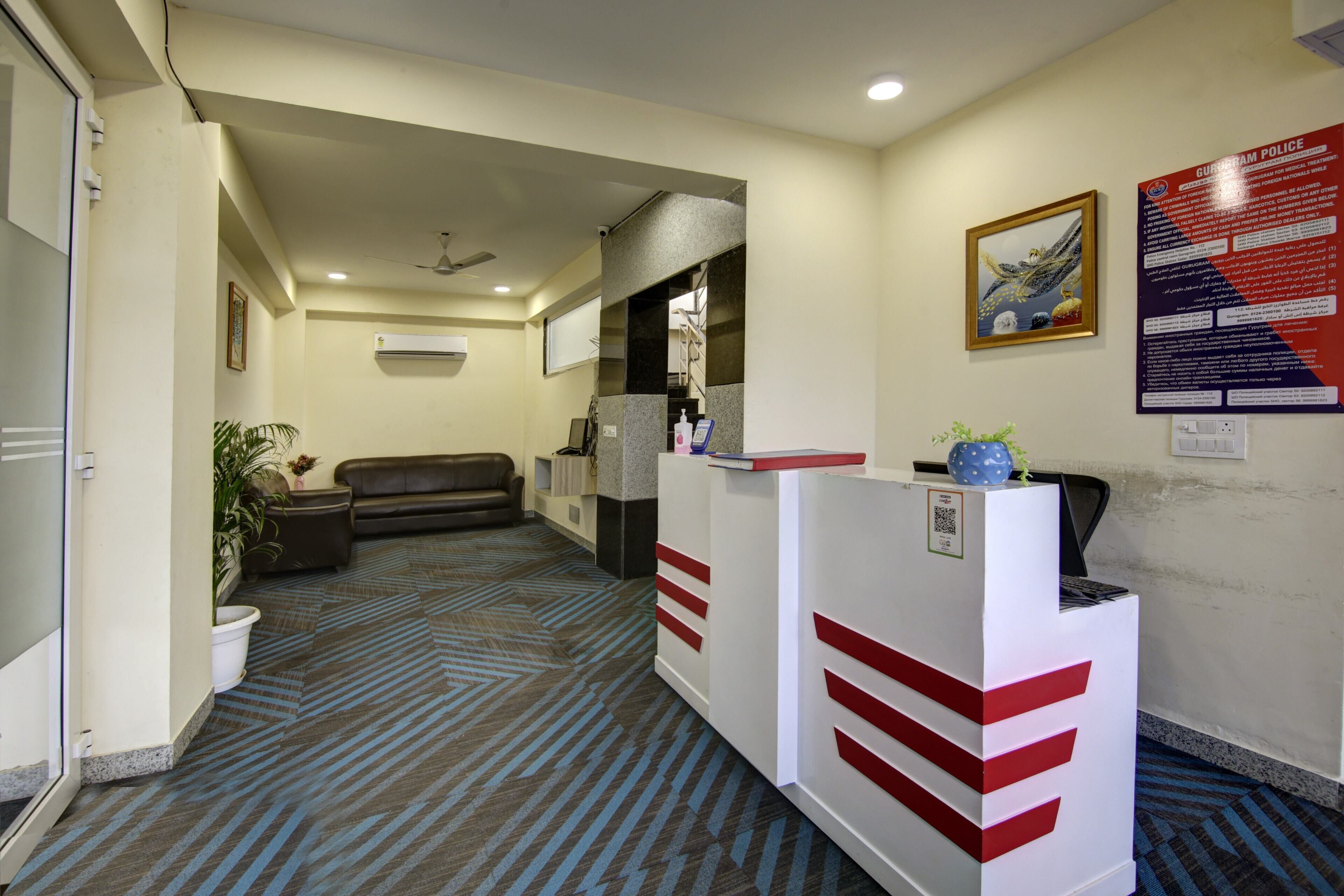 A reception area with a reception desk, a couch, a potted plant, and a wall-mounted sign.