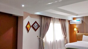 A hotel room with a bed, a green sofa, a chair, a small table, and a ceiling light. - Golden Tulip Hotel PH-GTPH (Port Harcourt)