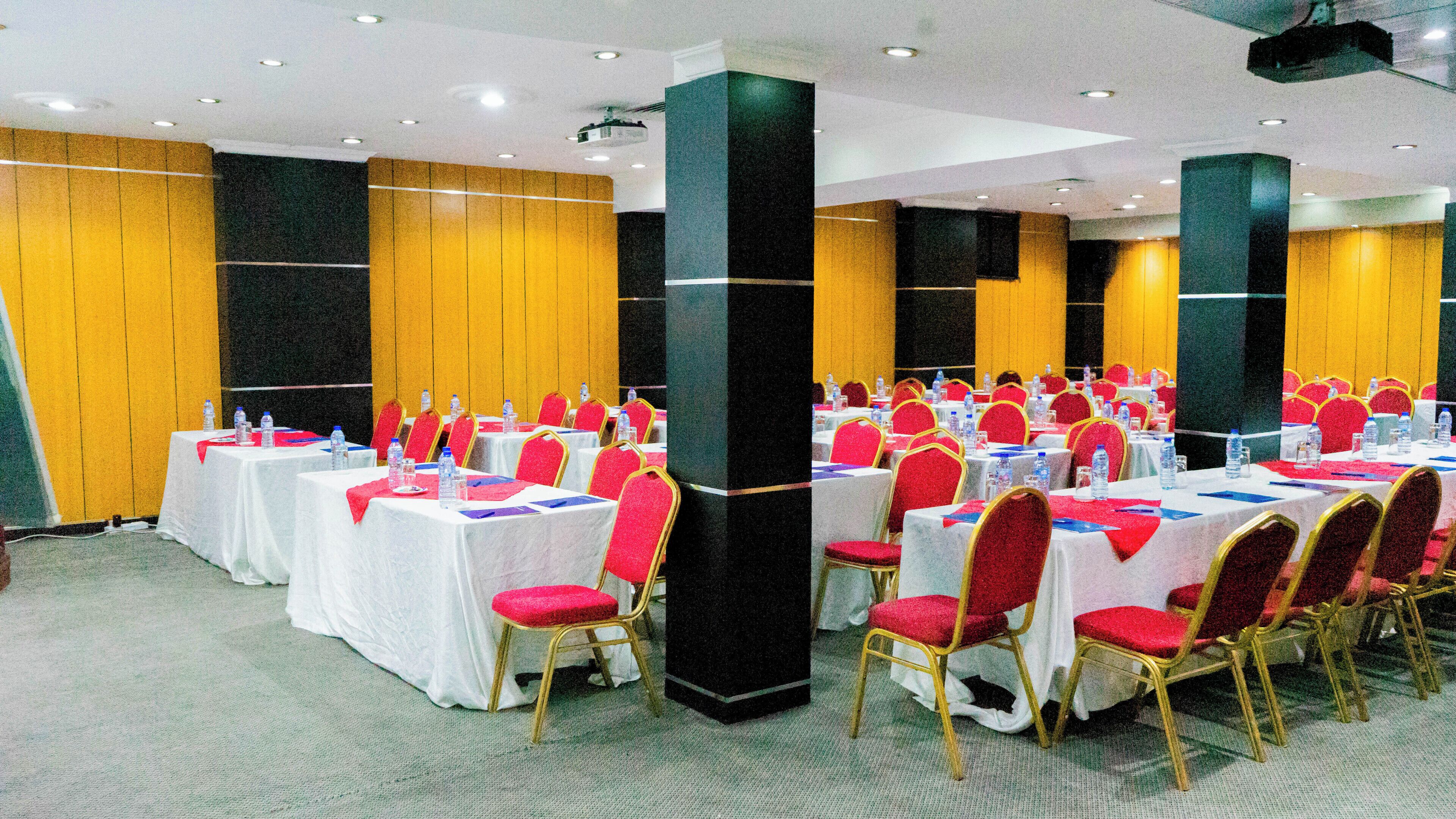 A conference room with multiple tables and chairs, equipped with water bottles and nameplates.