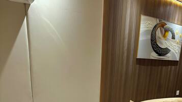 Un espacio de oficina moderno con un escritorio blanco, una computadora portátil, una silla blanca y un sofá color beige.