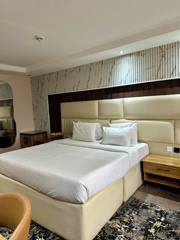 A modern hotel room with a large bed, a headboard with vertical lines, a bedside table, and a nightstand.