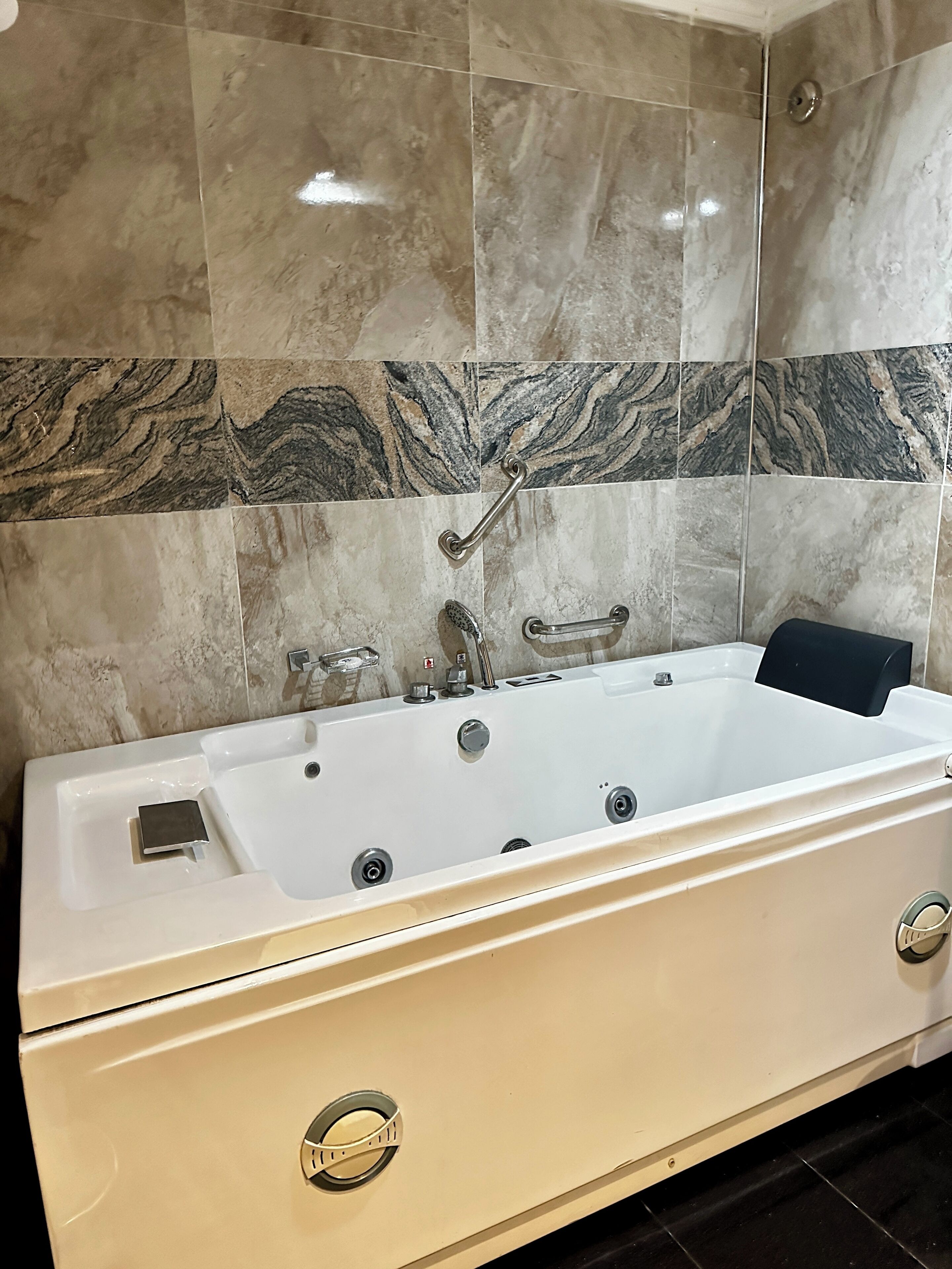 Une salle de bain avec une baignoire blanche, une douchette à main et un meuble-lavabo avec un évier.