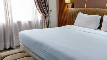 A hotel room with a large bed, a wall-mounted air conditioner, and a window with curtains.