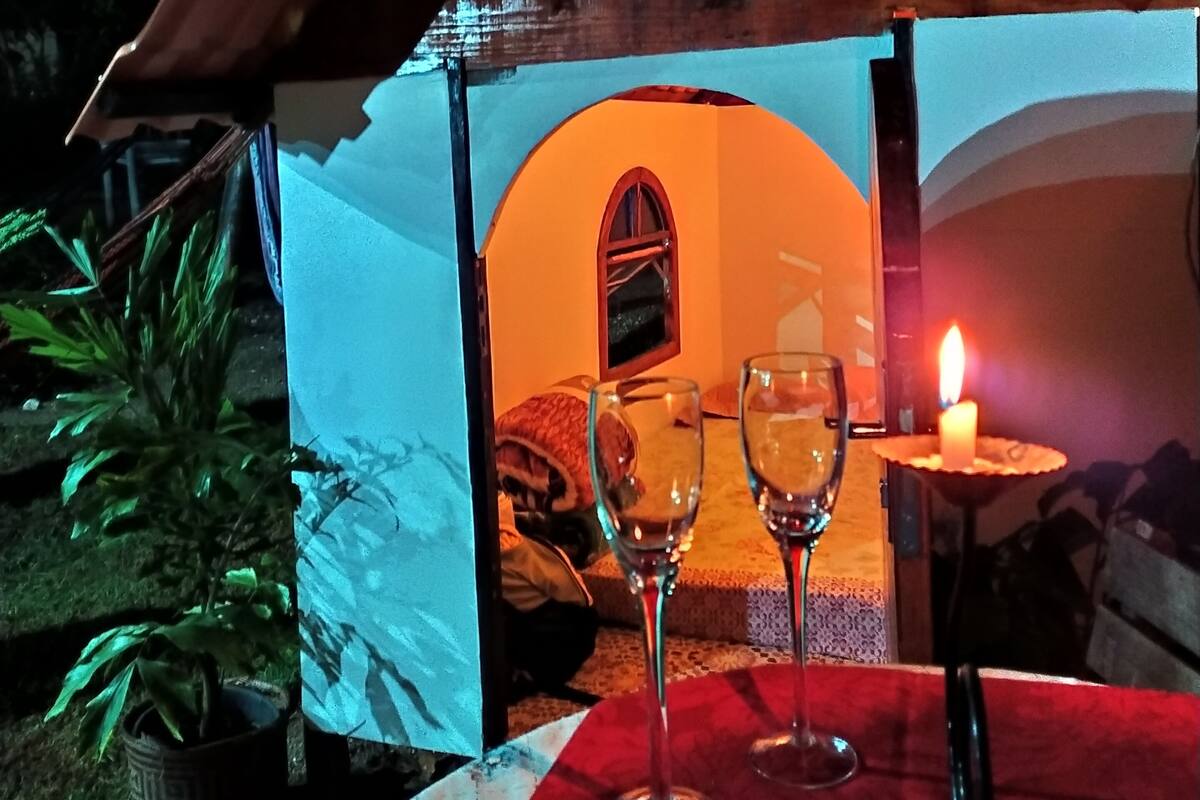 A cozy outdoor dining area with a table set for two, featuring two wine glasses and a candle.