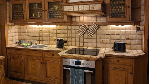 A kitchen with wooden cabinets, a tiled backsplash, a stainless steel dishwasher, and a coffee maker. - WaldHausen, free WiFi and Netflix (Mömlingen)