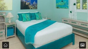 Een slaapkamer met een bed, nachtkastje, dressoir en twee aan de muur gehangen schilderijen.