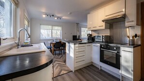 A modern kitchen with white cabinets, a black countertop, and stainless steel appliances. - Rivendell House located close to Fort William (Spean Bridge)