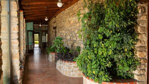 A corridor with stone walls and wooden beams, leading to a door with a view of greenery outside. - Villa in Trivigno with 9 bedrooms sleeps 18 (Trivigno)