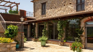 A stone building with a courtyard, potted plants, and a wooden pergola. - Villa in Trivigno with 9 bedrooms sleeps 18 (Trivigno)