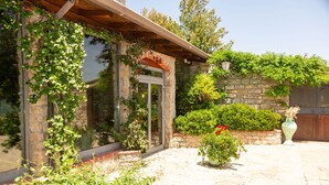 A stone building with a wooden pergola, a glass door, and a stone wall with climbing plants. - Villa in Trivigno with 9 bedrooms sleeps 18 (Trivigno)