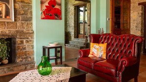 A cozy room with a fireplace, a red leather sofa, and a painting of red flowers on the wall. - Villa in Trivigno with 9 bedrooms sleeps 18 (Trivigno)