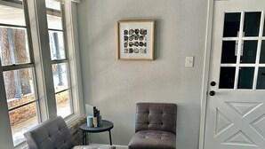 A room with a dark wood floor, a grey upholstered sofa, a matching armchair, a small round table with books, and a framed picture on the wall. - Agreeable Gray: 3 Bedroom, Soothing 5 Beds, Large groups, Pet Friendly

 (Tyler)