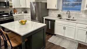 A modern kitchen with white cabinets, stainless steel appliances, and a central island with a bowl of fruit. - Agreeable Gray: 3 Bedroom, Soothing 5 Beds, Large groups, Pet Friendly

 (Tyler)
