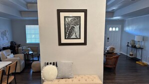 A living room with a bench, a framed artwork, and a dining area with chairs and a table. - Agreeable Gray: 3 Bedroom, Soothing 5 Beds, Large groups, Pet Friendly

 (Tyler)