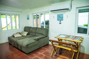 A living room with a sofa, a wooden table, and a view of the outside. - Racho El Ancla La Libertad, San Diego w/Wi-Fi & AC (San Diego)