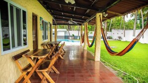 Un porche cubierto con piscina, mesas y sillas de madera.
