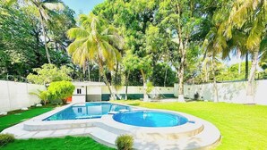 Una piscina con diseño geométrico, rodeada por un césped cuidado y palmeras.