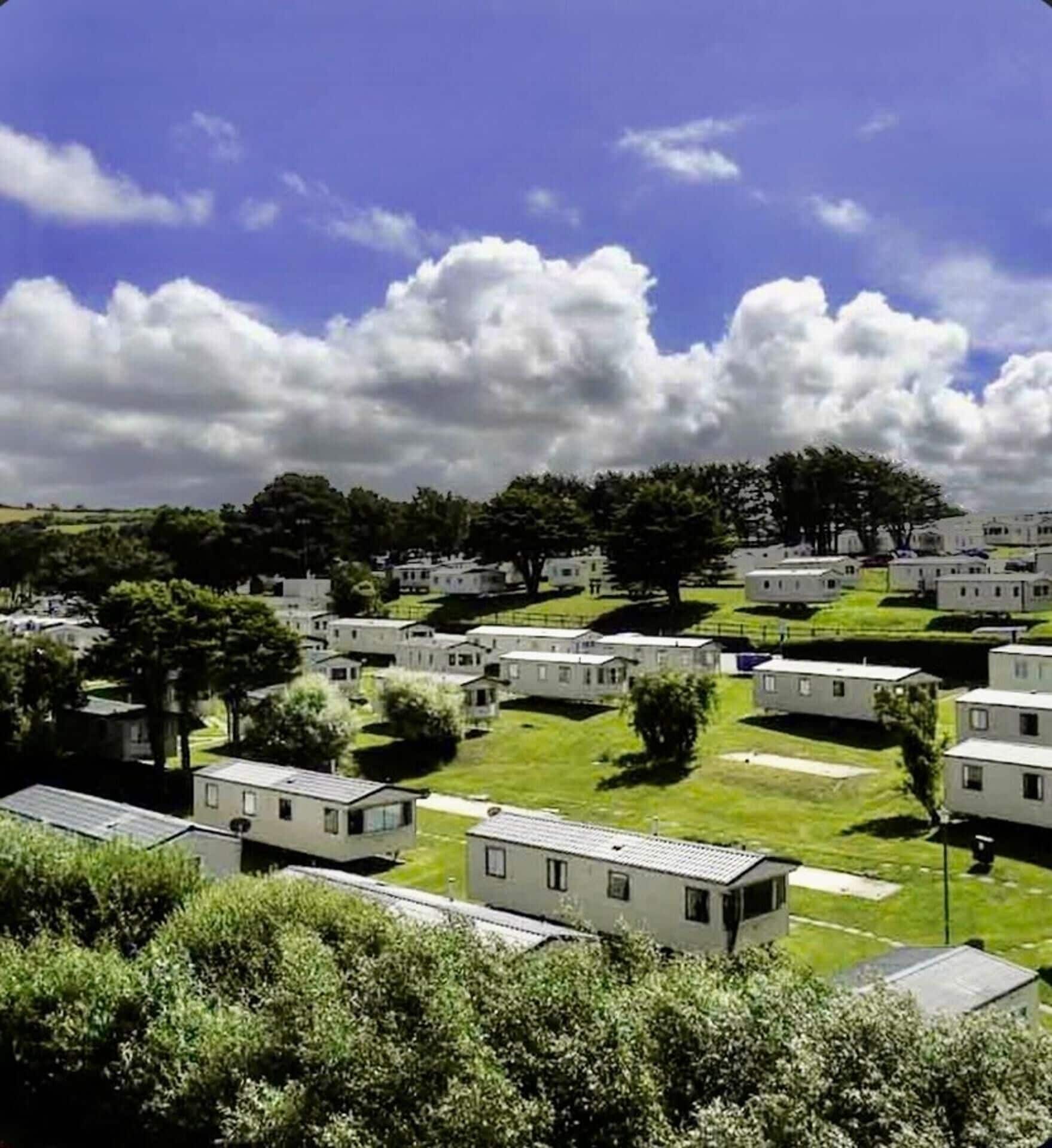 A series of mobile homes arranged in rows with green lawns and trees in the background.