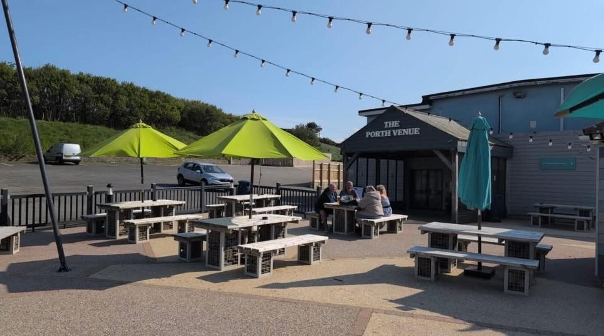 An outdoor seating area with tables and chairs, a covered pavilion, and a building labeled 'The Porth Venue.'