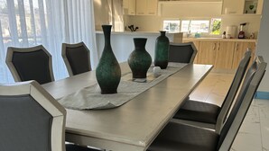A dining area with a long table, six chairs, and three green vases.