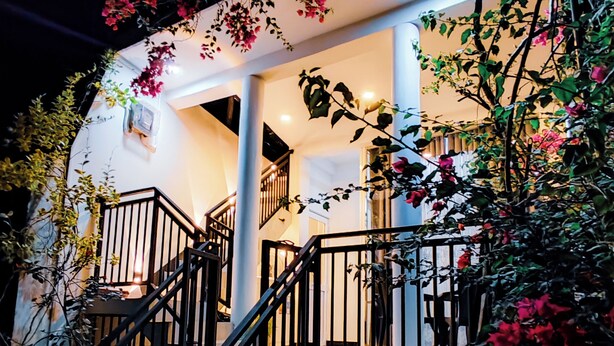 A staircase with black railings leading to a white door, surrounded by various plants and flowers. - Flower shade villa (Weligama)
