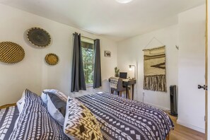 A bedroom with two beds, a desk with a computer, a window with curtains, and wall decorations. - Elegant A-Frame w/ Hot Tub Views! Close to town, skiing, & hiking! (Evergreen)