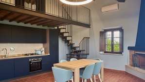 A modern kitchen with a wooden table and chairs, a staircase, and a window with a view. - Podere Sant'Antonio (Asciano)