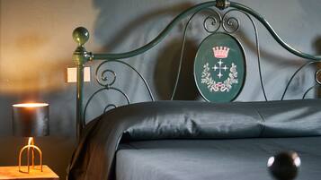 Een bed met een groen hoofdeinde, een bedlamp en een klein tafeltje met een lamp.