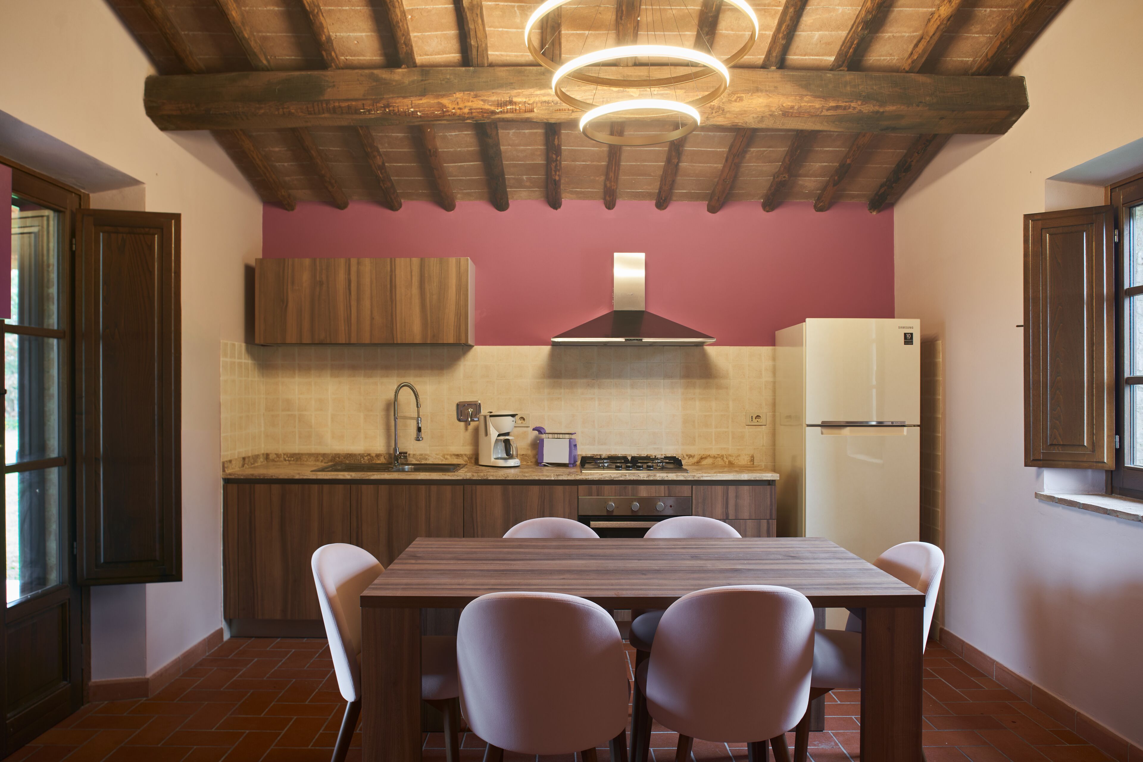 A kitchen with a wooden table and chairs, a stove, a sink, and a refrigerator.