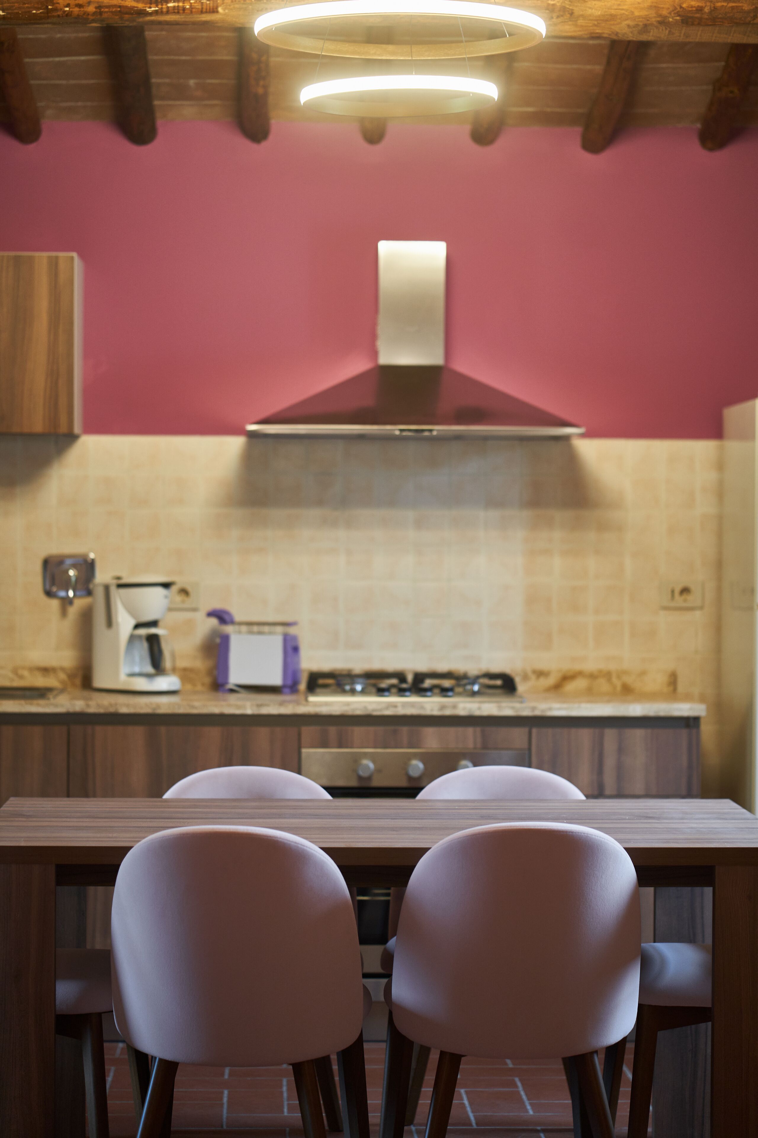 A kitchen with a wooden table and two chairs, a gas stove, and a coffee maker.
